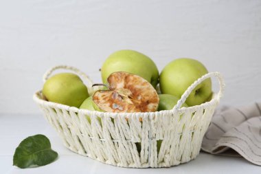 Şımarık elma ve iyi olanlar beyaz masada sepette.