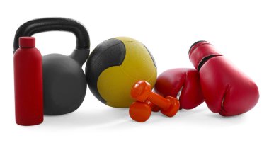 İlaç topu, kettlebell, dambıl, boks eldiveni ve su şişesi beyaza izole edilmiş.