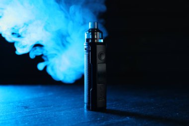 Siyah masada mavi ışıkta elektronik sigara içen cihaz