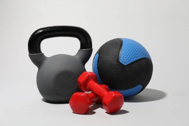 İlaç topları, kettlebell ve açık gri arkaplanda dambıllar