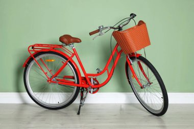 Açık yeşil duvarın yanında sepeti olan kırmızı bisiklet.