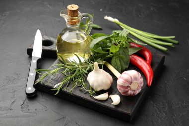 Farklı taze otlar, baharatlar ve bıçak siyah masada, yakın plan.