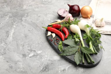 Farklı taze otlar, sarımsak, soğan ve diğer baharatlar gri masada. Metin için boşluk