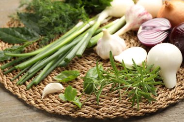 Farklı taze otlar, soğanlar ve sarımsak ahşap masada, yakın plan.