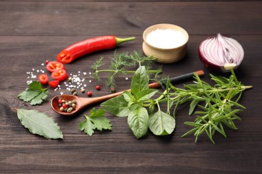 Farklı taze otlar ve baharatlar ahşap masada, yakın plan.