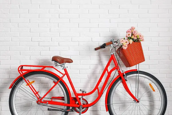 Beyaz tuğla duvarın yanında bir sepet güzel çiçekli bisiklet.