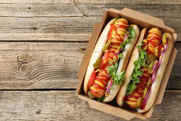 Sebzeli, hardallı ve ketçaplı lezzetli sosisliler, ahşap masa, üst manzara. Metin için boşluk