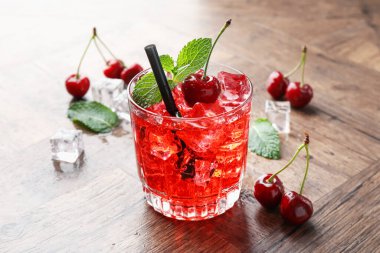 Buzlu vişneli gazoz, böğürtlen ve nane şekeri ahşap masada, yakın plan.
