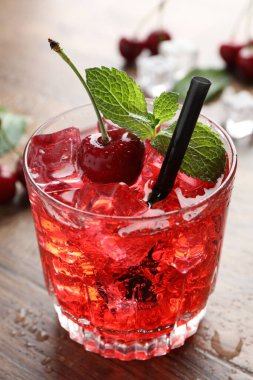 Buzlu vişneli gazoz, böğürtlen ve nane şekeri ahşap masada, yakın plan.