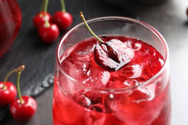 Buzlu vişneli gazoz ve gri masada cam meyveler, yakın plan.