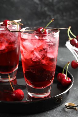 Buzlu vişneli gazoz ve bardaklar gri masada, yakın plan.