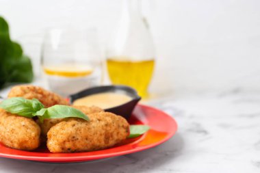 Lezzetli kızarmış kroket, fesleğen ve sos beyaz mermer masada servis edilir, yakın plan. Metin için boşluk