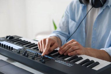 İçerideki masada MIDI klavyesiyle çalışan adam, yakın plan.