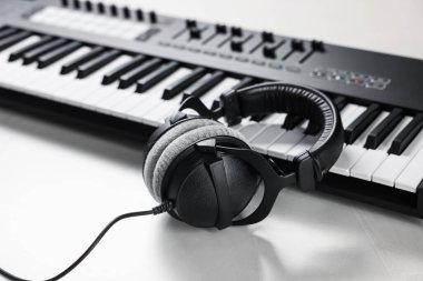 Beyaz masada kulaklıklı MIDI klavyesi, yakın plan.