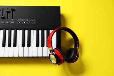 Sarı arka planda kulaklıklı MIDI klavyesi, üst görüş. Metin için boşluk