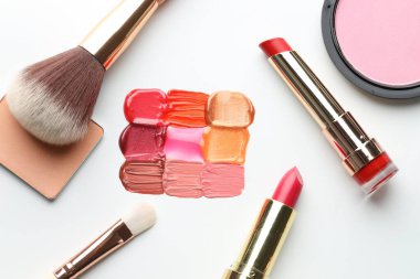 Beyaz arka planda farklı kozmetik ürünler ve makyaj fırçaları, düz yatış