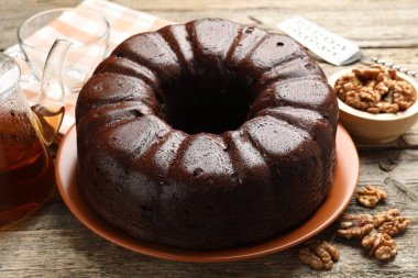 Lezzetli çikolatalı kek, ceviz ve çay ahşap masada, yakın plan.