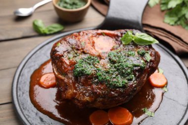 Biftek ve soslu geleneksel ossobuko tabağı ahşap masada servis edilir.