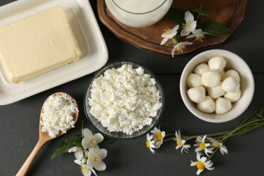 Taze süt ürünleri ve çiçekler gri ahşap masada, düz yatıyordu.
