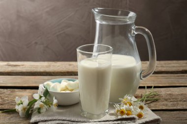 Taze süt, mozarella topları ve ahşap masada çiçekler, yakın plan. Süt ürünleri