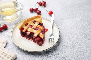 Gri dokulu masada bir parça kirazlı turta, çilek ve çay. Metin için boşluk