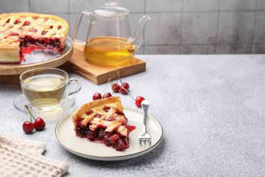 Lezzetli vişneli turta, kiremitli duvara karşı gri desenli masa üzerinde çilek ve çay. Metin için boşluk