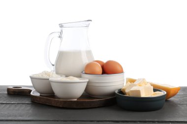 Gri ahşap masada beyaz arka planda farklı süt ürünleri ve yumurtalar