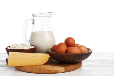 Farklı süt ürünleri ve yumurtalar beyaz arka plana karşı ahşap masa üzerinde