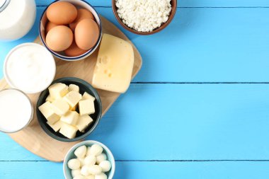 Farklı süt ürünleri ve yumurtalar açık mavi ahşap masada, düz yerde. Metin için boşluk