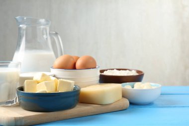 Açık mavi ahşap masa üzerinde farklı süt ürünleri ve yumurtalar, yakın plan. Metin için boşluk