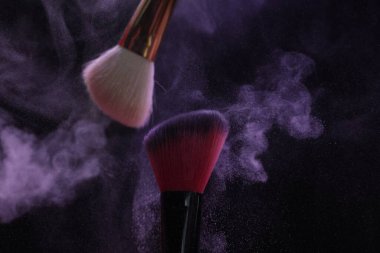 Siyah arka planda mor göz farlı makyaj fırçaları, yakın plan