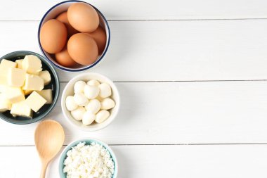 Farklı süt ürünleri ve yumurtalar beyaz ahşap masada, düz yerde. Metin için boşluk