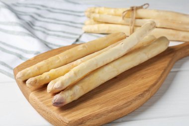 Beyaz ahşap masada çiğ kuşkonmaz mızrakları, yakın plan.