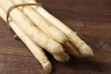 Ahşap masada çiğ beyaz kuşkonmaz mızrakları, yakın plan.