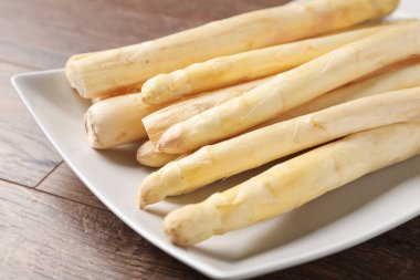 Ahşap masada çiğ beyaz kuşkonmaz mızrakları, yakın plan.