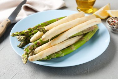 Gri masada farklı çiğ kuşkonmaz mızrakları ve baharatlar, yakın plan.