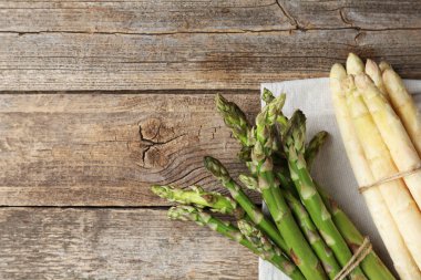 Ahşap masada farklı çiğ kuşkonmaz mızrakları, üst manzara. Metin için boşluk