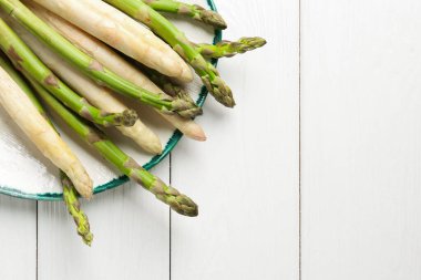Beyaz ahşap masada farklı çiğ kuşkonmaz mızrakları, üst manzara. Metin için boşluk