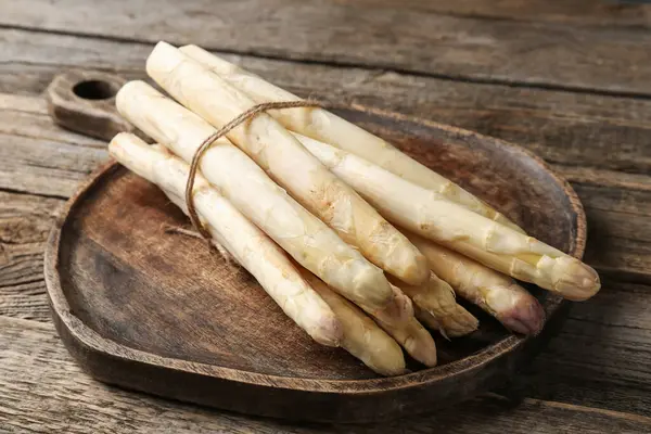 Ahşap masada çiğ beyaz kuşkonmaz mızrakları, yakın plan.