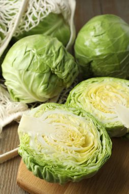 Taze lahanalar ve ahşap masada ağ torba, yakın plan.