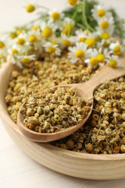 Kuru, taze papatya çiçekleri kasede ve kaşık açık ahşap masada, yakın plan