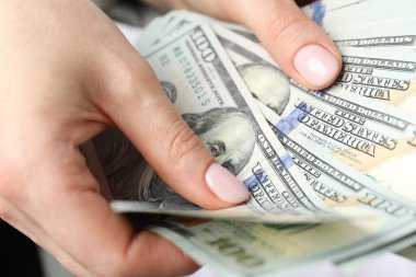 Kadın içeride dolar sayıyor, yakın çekim manzarası var.