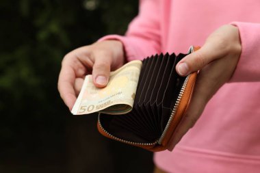 Dışarıdaki cüzdana para koyan kadın, yakın plan.