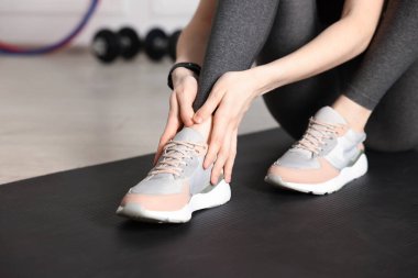Spor sakatlığı. Spor salonunda bacak ağrısı çeken genç bir kadın, yakın plan.