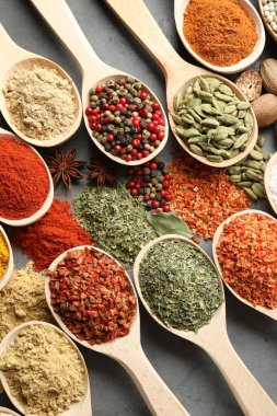 Gri masadaki kaşıklardaki farklı baharatlar düzdü.