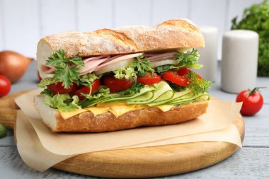 Jambonlu, peynirli ve sebzeli baget sandviç. Ahşap masa, gri arka plan, yakın plan.