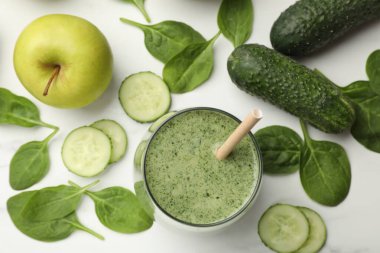 Lezzetli ıspanaklı smoothie ve malzemeler beyaz masada, düz yerde.