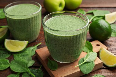 Lezzetli ıspanaklı smoothie ve ahşap masada malzemeler, yakın plan.