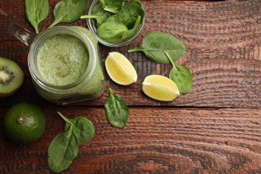 Mason kavanozunda leziz bir smoothie, ıspanak yaprakları, ahşap masada limon ve kivi, düz yatak. Metin için boşluk