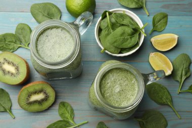 Mason kavanozlarında nefis bir smoothie, ıspanak yaprakları, kivi ve limon açık mavi ahşap masa, düz uzanmış